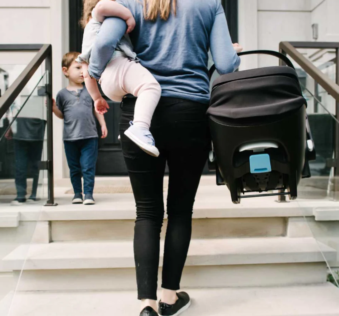 woman holding baby and clek car seat