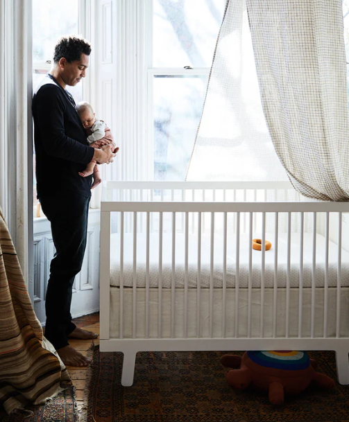 man holding baby by Oeuf crib
