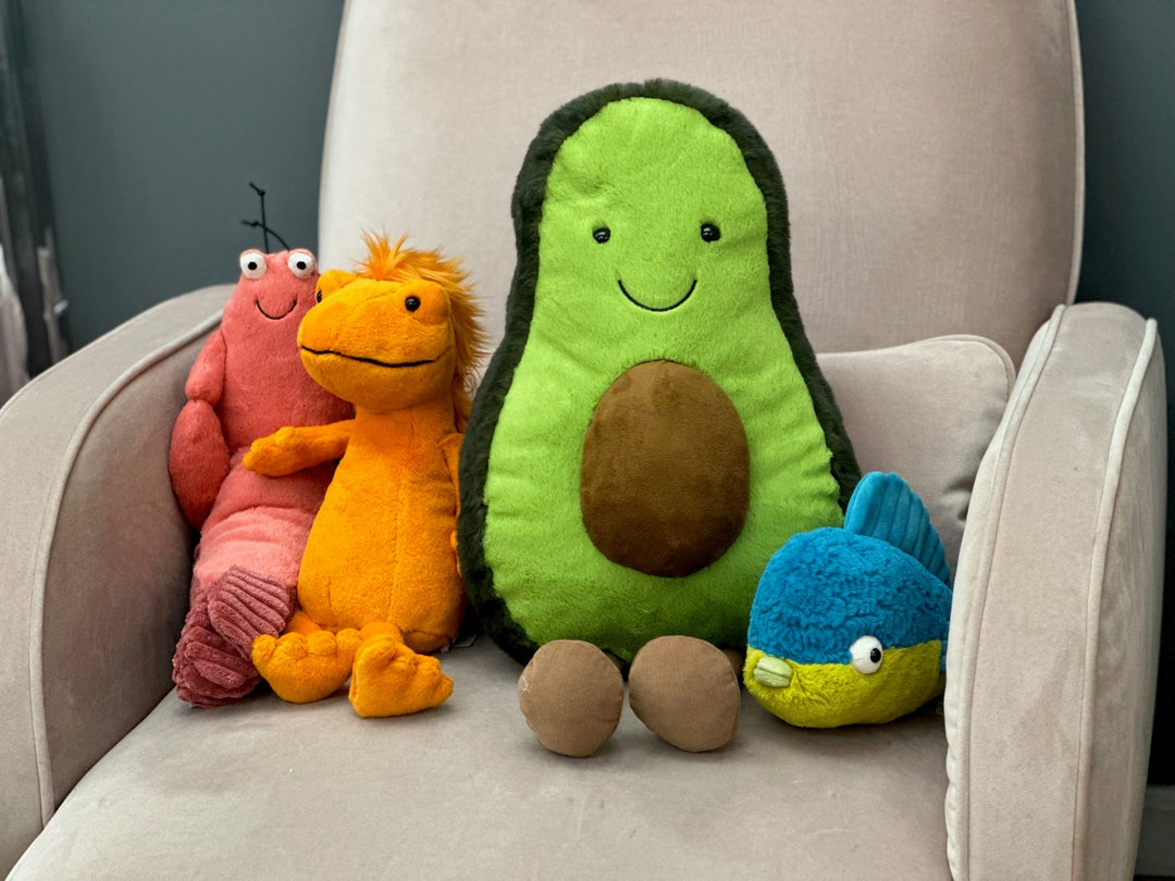 stuffed animals in rainbow colors sitting on a rocker
