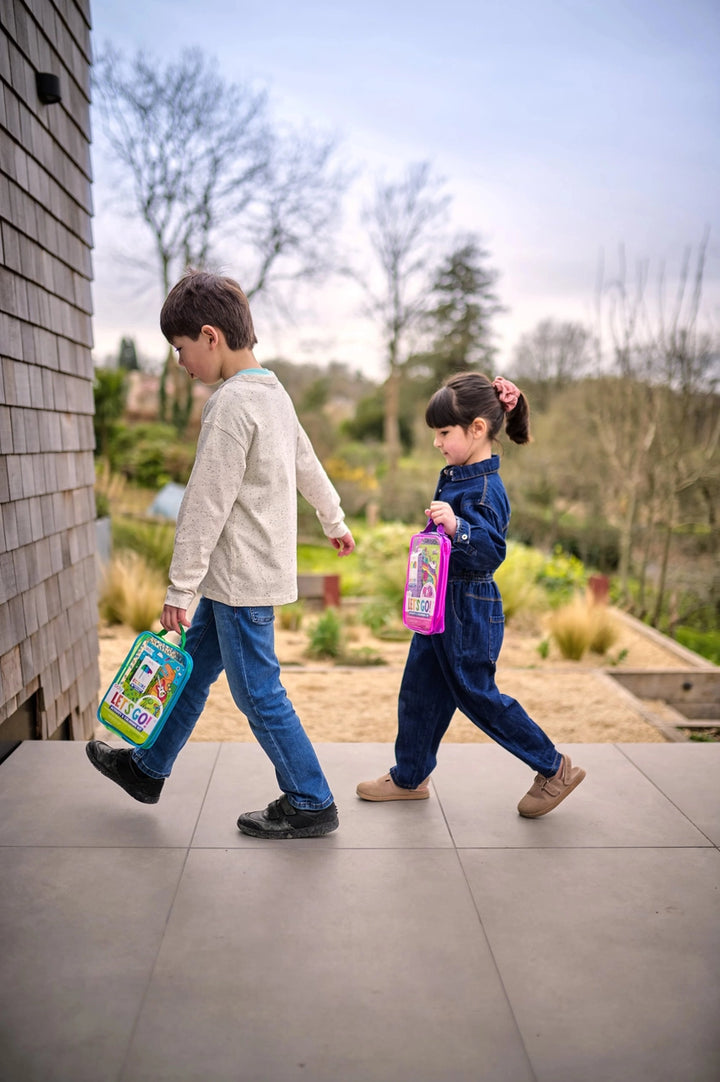 Two children walking outdoors with books, one holding a colorful book and the other a pink book.