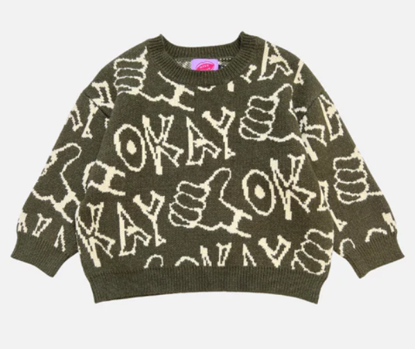 Children’s oversized crewneck sweater in pink with hand-drawn ‘okay’ lettering and thumbs-up doodle, laid flat to show boxy fit and ribbed trim