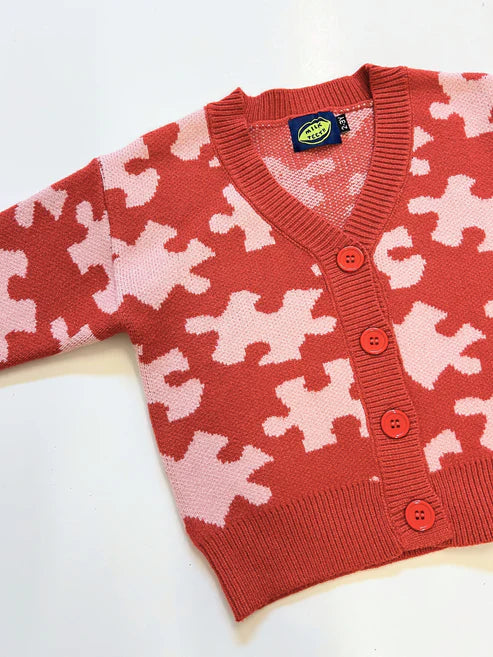 Milk Teeth Red Puzzle Sweater featuring playful geometric knit pattern in soft cotton, laid flat on a neutral background