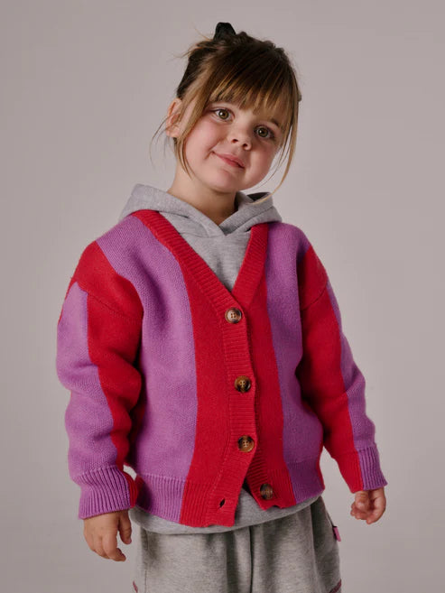Children’s cardigan with bold pink & purple stripes, button-up front, and relaxed fit, laid flat to show knit texture and design