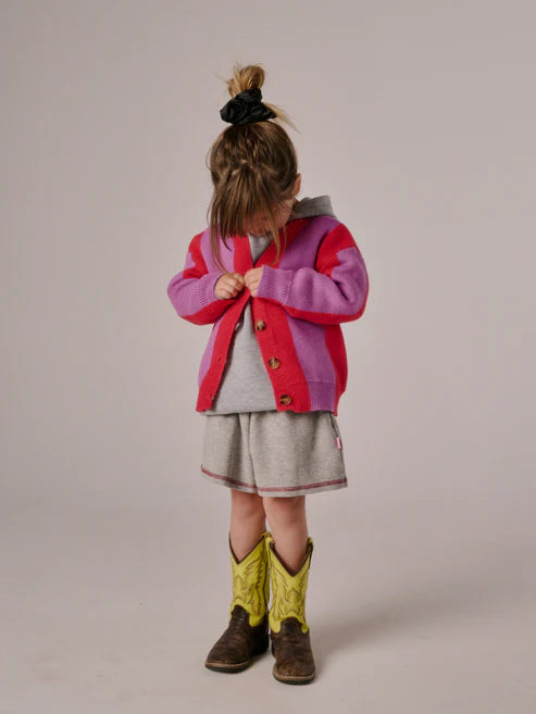 Children’s cardigan with bold pink & purple stripes, button-up front, and relaxed fit, laid flat to show knit texture and design