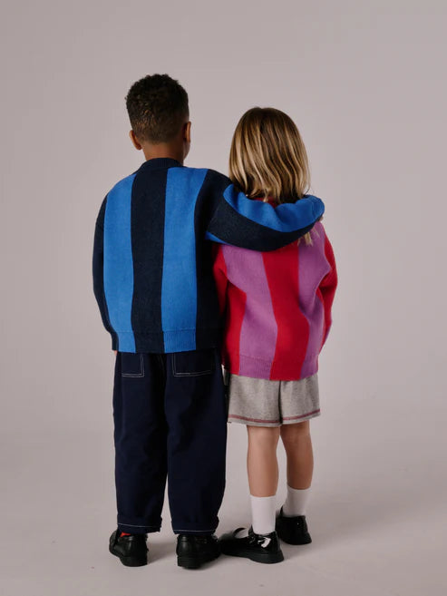 Children’s cardigan with bold pink & purple stripes, button-up front, and relaxed fit, laid flat to show knit texture and design