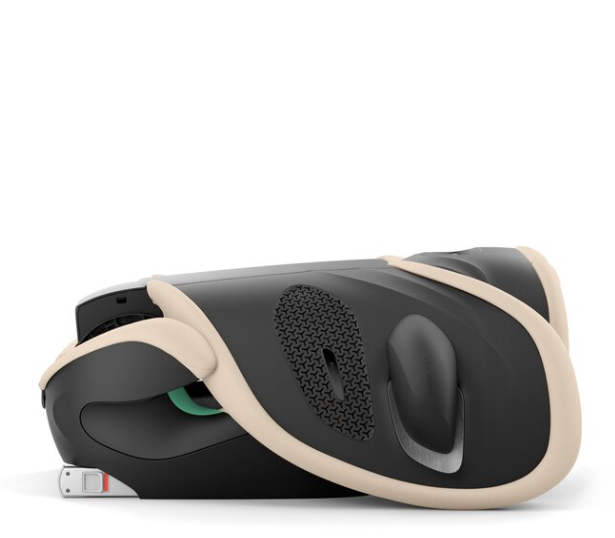 A side profile view of a black and beige baby car seat, showing the side panel with a textured vent, a smooth black insert, and a small white latch connector on a clean white background.